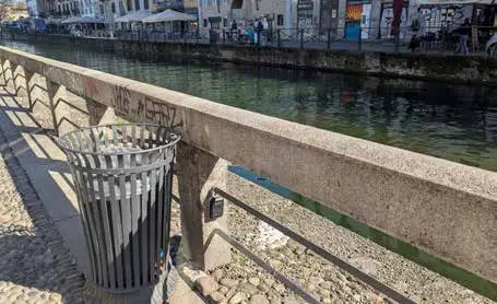 Un cestino e il parapetto di un Naviglio di Milano