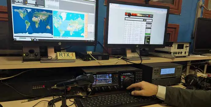 Postazione radio con ricetrasmettitori, monitor e mappe del mondo